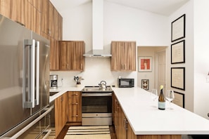 Una cocina moderna con armarios de madera, electrodomésticos de acero inoxidable y encimera blanca.