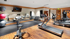 Ein gut ausgestattetes Fitnessstudio mit Laufbändern, Crosstrainern und Kurzhanteln.
