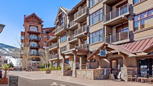 Ein mehrstöckiges Hotel mit Balkonen und einer Skipiste im Hintergrund, mit einem Schild für Aspen Sports.