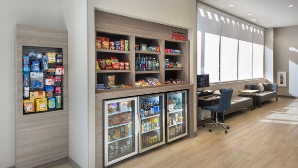 A hotel lobby with a seating area, a refreshment kiosk, and a reception desk.