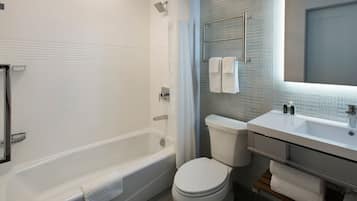 Un baño moderno con bañera, inodoro y tocador con espejo.