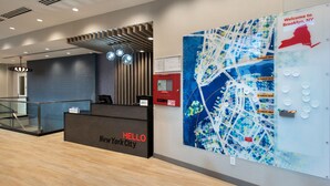 A reception area with a 'HELLO New York City' sign, a map of Brooklyn, NY, and a 'Welcome to Brooklyn, NY' sign.