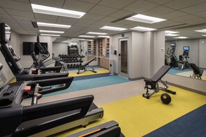 Une salle de sport équipée de tapis de course, de vélos elliptiques et de poids libres.