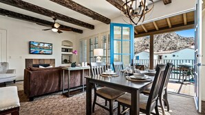 A spacious dining area with a view of the mountains, a cozy seating area with a fireplace, and a modern kitchen with large windows.