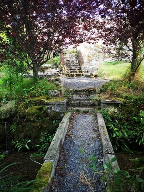 A stone staircase leading to a stone structure, surrounded by greenery and moss. - Lovely 3-bed House at Clashganny Mill, Borris (Clashganny)
