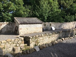A stone building with a sloped roof, a wheel, and a small opening. - Lovely 3-bed House at Clashganny Mill, Borris (Clashganny)