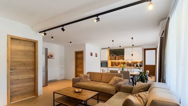 A modern living room with a sectional sofa, a coffee table, and a dining area in the background. - Four Bedroom Holiday Home (Turjaci)