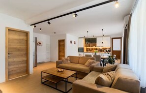 A modern living room with a sectional sofa, a coffee table, and a dining area in the background.