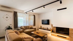 A modern living room with a sectional sofa, a coffee table, a flat-screen TV, and a fireplace. - Four Bedroom Holiday Home (Turjaci)