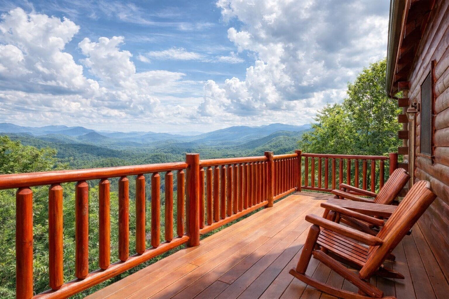 A wooden deck with a railing, wooden rocking chairs, and a view of a mountainous landscape.