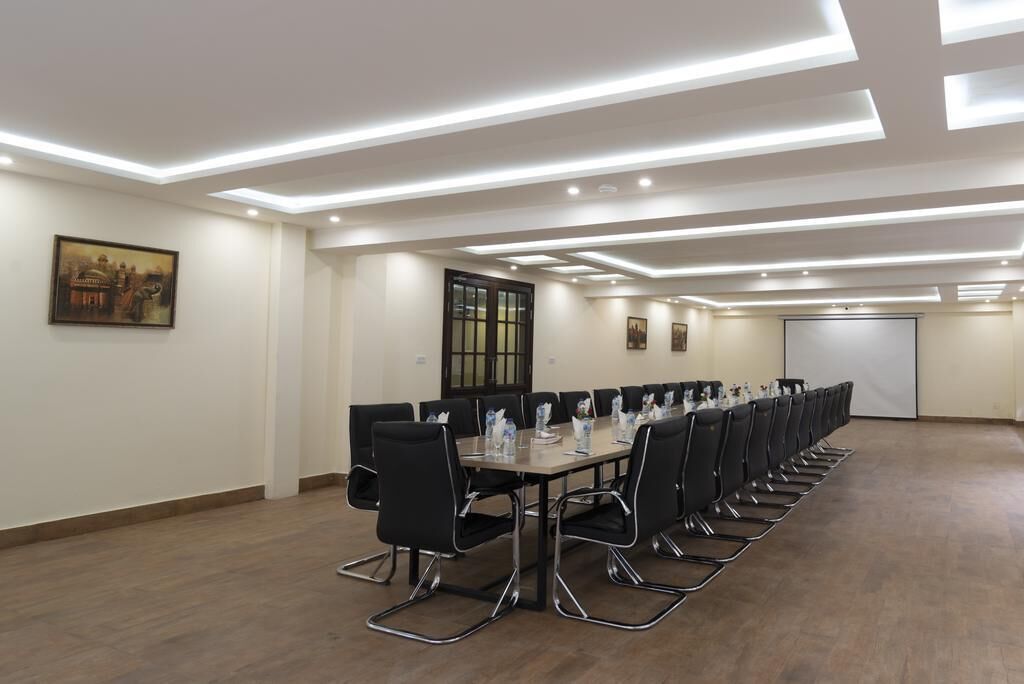 Une salle de conférence avec une longue table, des chaises noires et un éclairage encastré.