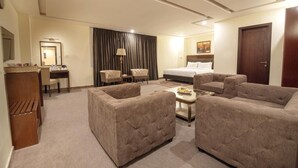 A hotel room with a bed, two armchairs, a sofa, a desk with a lamp, and a wardrobe. - Hotel One Naran (Balakot)