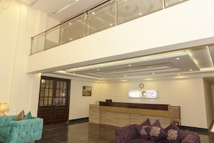 A hotel reception area with a reception desk, a clock, and a sign that reads "HOTEL ONE".