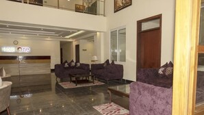 A modern hotel lobby with two purple sofas, a glass coffee table, and a marble floor. - Hotel One Naran (Balakot)