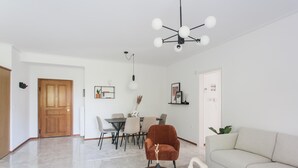 En moderne stue med spiseområde, sofa, sofabord og en lysekrone.