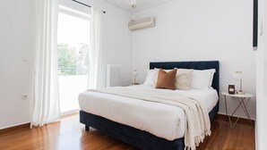 Et soveværelse med seng, radiator, klimaanlæg, et vindue med gardiner og et natbord med lampe.