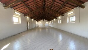 A spacious indoor area with a high ceiling and tiled floor, featuring multiple windows and doors along the walls. - Casale Colle dei Pini (Anguillarese-colle Due Pini)