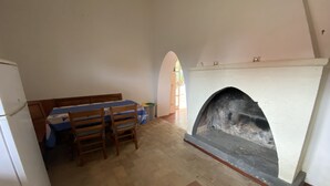 A dining area with a table and chairs, a fireplace, and a tiled floor. - Casale Colle dei Pini (Anguillarese-colle Due Pini)