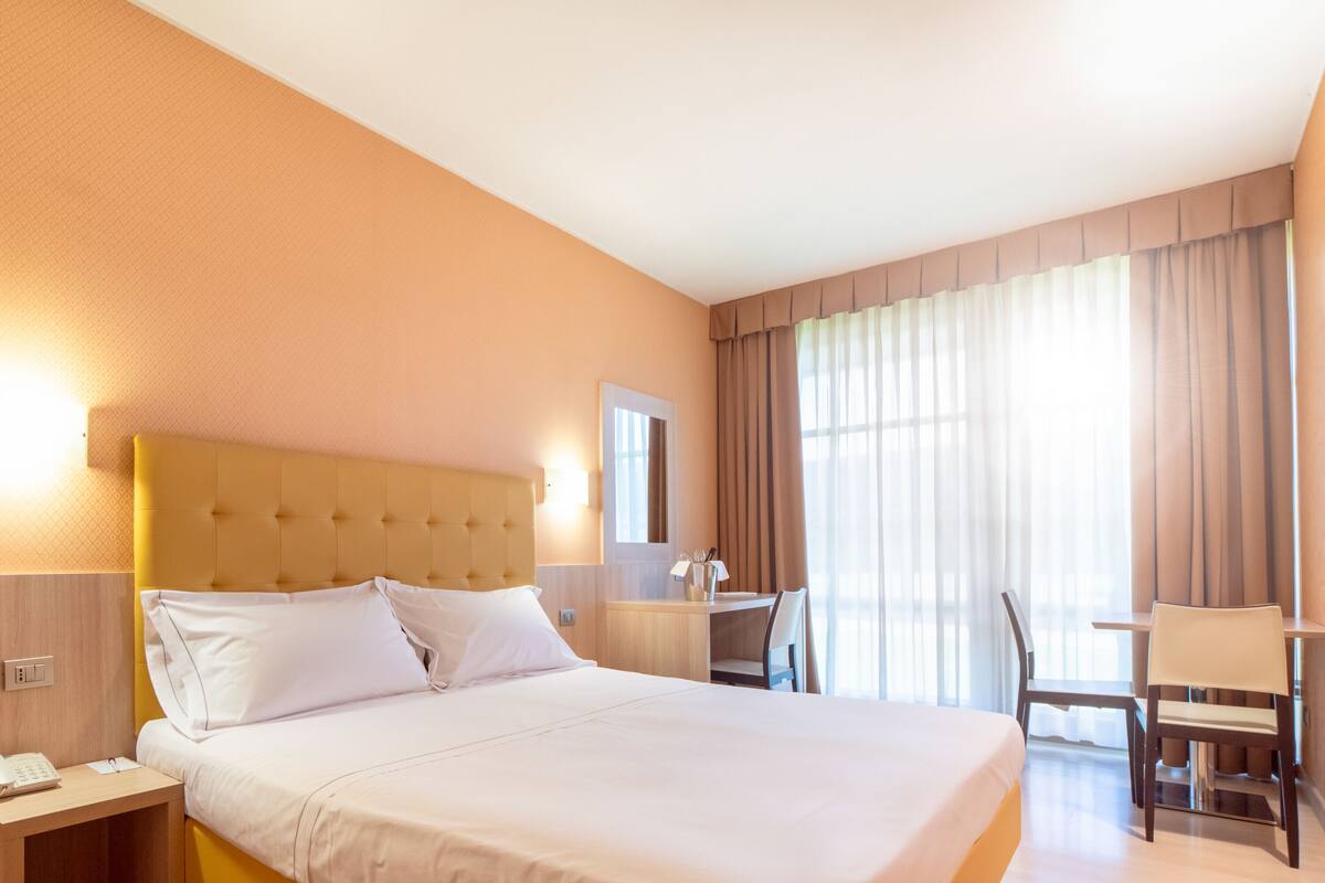 Een hotelkamer met een groot bed, een bureau en een stoel.