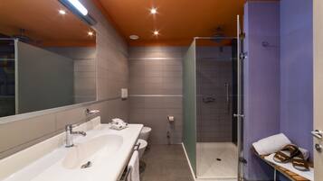 A modern bathroom with a large sink, toilet, and walk-in shower.