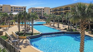 Een resort met meerdere zwembaden, omringd door palmbomen en liggedeeltes.