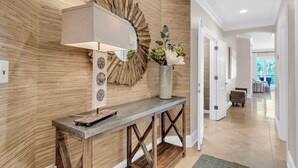 Een moderne receptie met een houten wand, een console tafel, een lamp en een vaas met bloemen.
