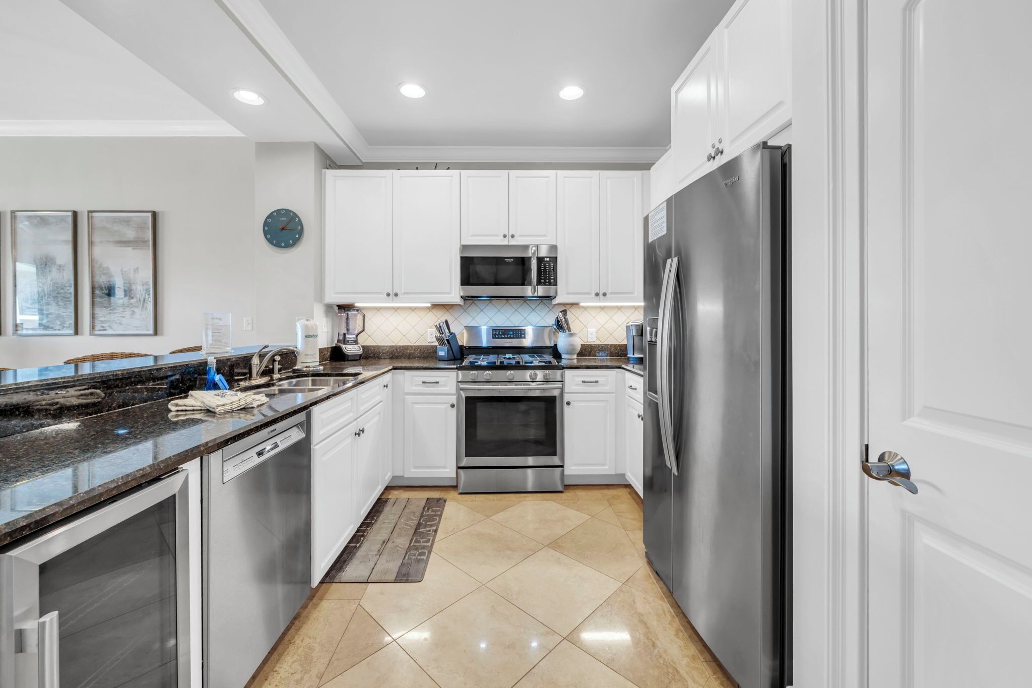 A modern kitchen with white cabinets, stainless steel appliances, and a granite countertop.