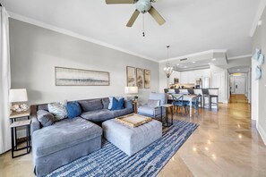 Uma sala de estar moderna com um sofá cinzento, um banquinho e um tapete azul.