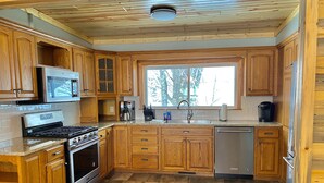 A kitchen with wooden cabinets, a stainless steel refrigerator, a microwave, a stove, and a dishwasher. - Snowmobile Friendly! Ample Parking-only 1 block to trail! Clean w cozy Fireplace (AuTrain)