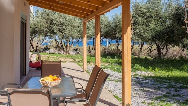 An outdoor patio with a table and chairs, a basket of fruit, and a red toy car. - Olive Tree Farm (Rethymno)