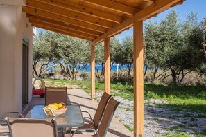 An outdoor patio with a table and chairs, a basket of fruit, and a red toy car. - Olive Tree Farm (Rethymno)