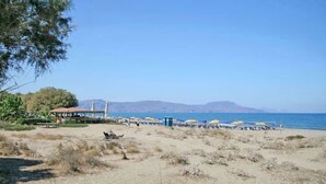 A beach with umbrellas and a pavilion. - Olive Tree Farm (Rethymno)