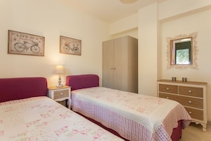A bedroom with two beds, a wardrobe, a dresser, and two wall-mounted bicycles. - Olive Tree Farm (Rethymno)