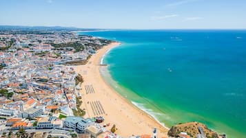 An aerial view of a coastal city with a long sandy beach and a clear blue sea.