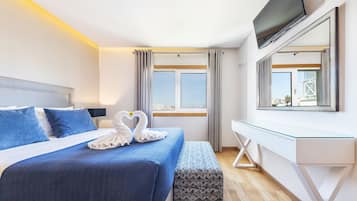 A modern hotel room with a bed, a desk, a TV, and a window with curtains.