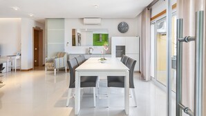 A modern kitchen with a white countertop, a green backsplash, and a hanging pot rack. - Flat Old Town OCV - 3min Beach (Albufeira)