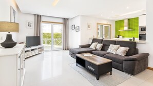 Ein modernes Wohnzimmer mit einem grauen Sofa, einem Flachbildfernseher und einem Holztisch.