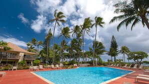A swimming pool with lounge chairs and palm trees. - Lae Nani 312, Oceanfront, AC,Tropical Bliss, Steps to Beach and Town (Kapaa)