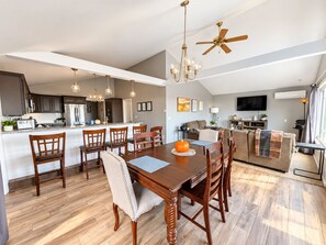Een moderne keuken met donkere kastjes, een centraal eiland en een eetgedeelte met houten stoelen en een tafel.