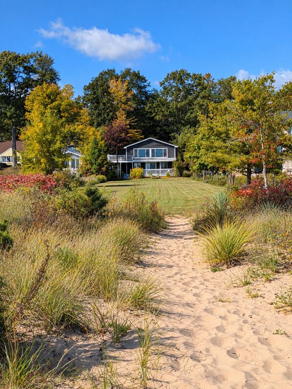 A pathway leading to a house with a front porch and a lawn.
