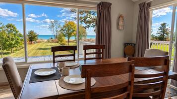 Un coin repas avec une table dressée pour quatre personnes, offrant une vue panoramique sur un terrain de golf et l’océan.