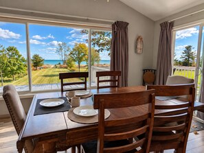Een eethoek met een tafel voor vier personen, met uitzicht op een golfbaan en de oceaan.