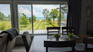 Comedor con vistas a un paisaje de pradera y una masa de agua a través de amplios ventanales.