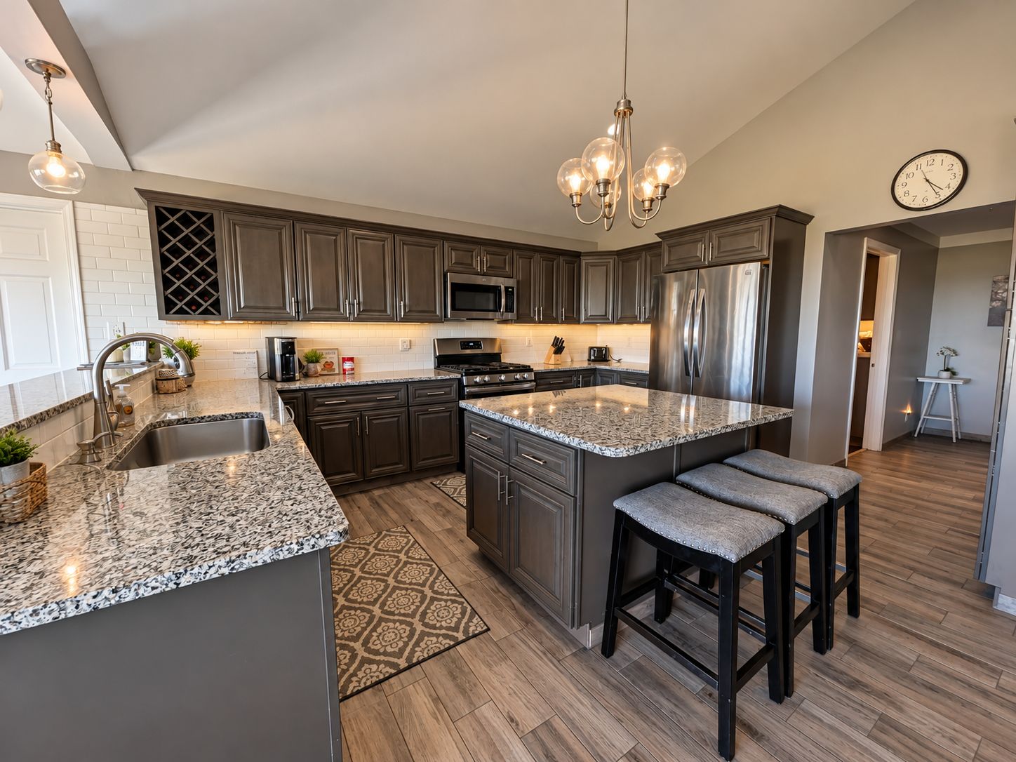A modern kitchen with granite countertops, stainless steel appliances, and a central island with bar stools.