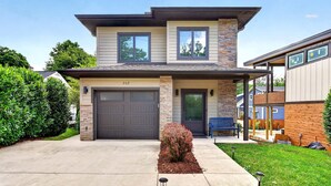 Une maison à deux étages avec un garage, un porche à l’avant et une pelouse bien entretenue.