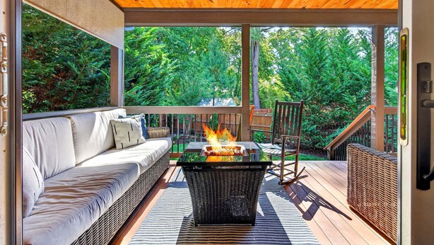 Une terrasse extérieure avec un foyer, un canapé et un fauteuil en osier.