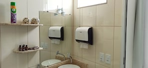 A bathroom with a sink, two hand dryers, a mirror, and shelves with toiletries. - Hotel Pousada Família de Nazaré (Cachoeira Paulista)