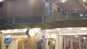 A multi-story building with a curved facade, glass railings, and a ground-level entrance with seating. - Hotel Pousada Família de Nazaré (Cachoeira Paulista)