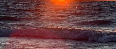 A sunset over the ocean with waves.