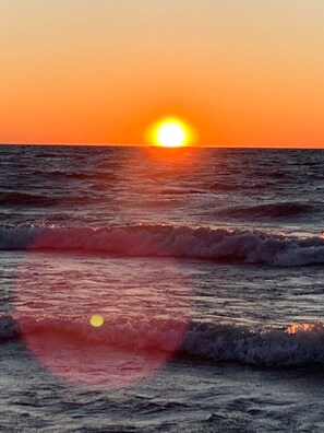 A sunset over the ocean with waves.